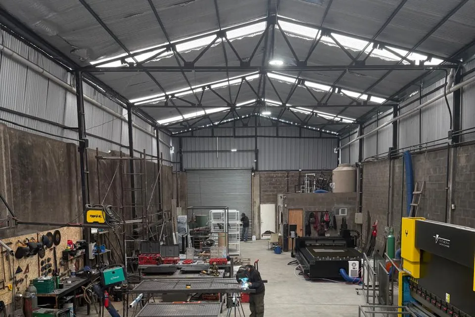 El galpón de Prymax en Garín: el láser de fibra, la plegadora CNC y un soldador trabajando en las mesas
